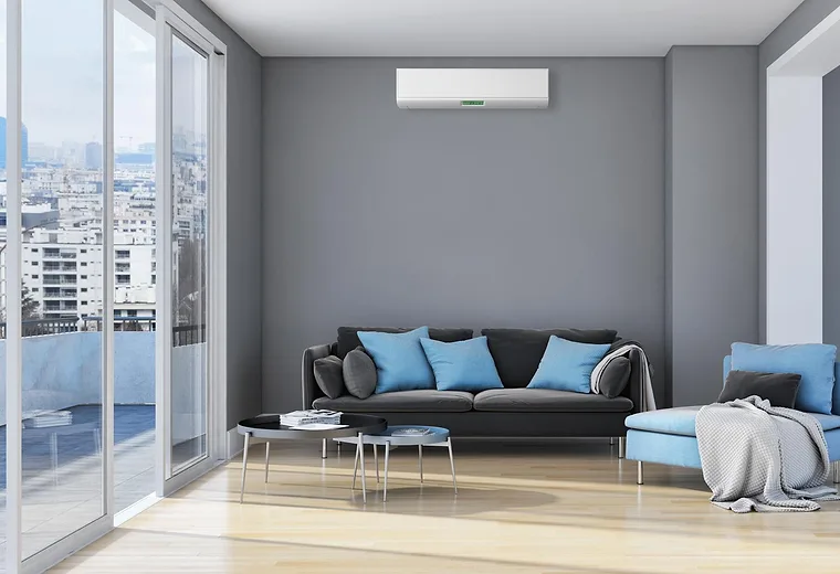 A bedroom with a wall-mounted split unit above the bed