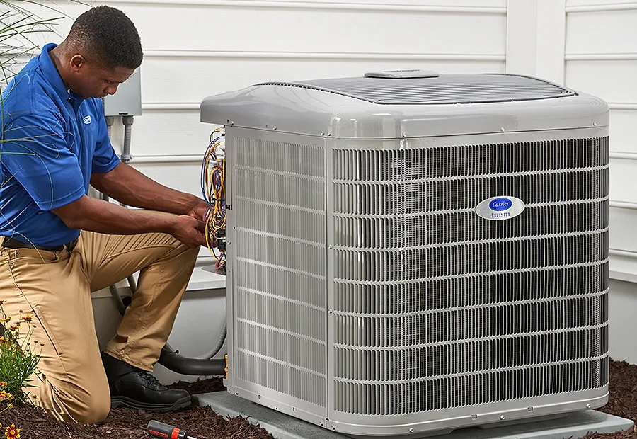 A technician checking an outdoor air-conditioning unit with manifold gauges